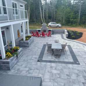 Large stone patio with dining and kitchen area, and fireplace.